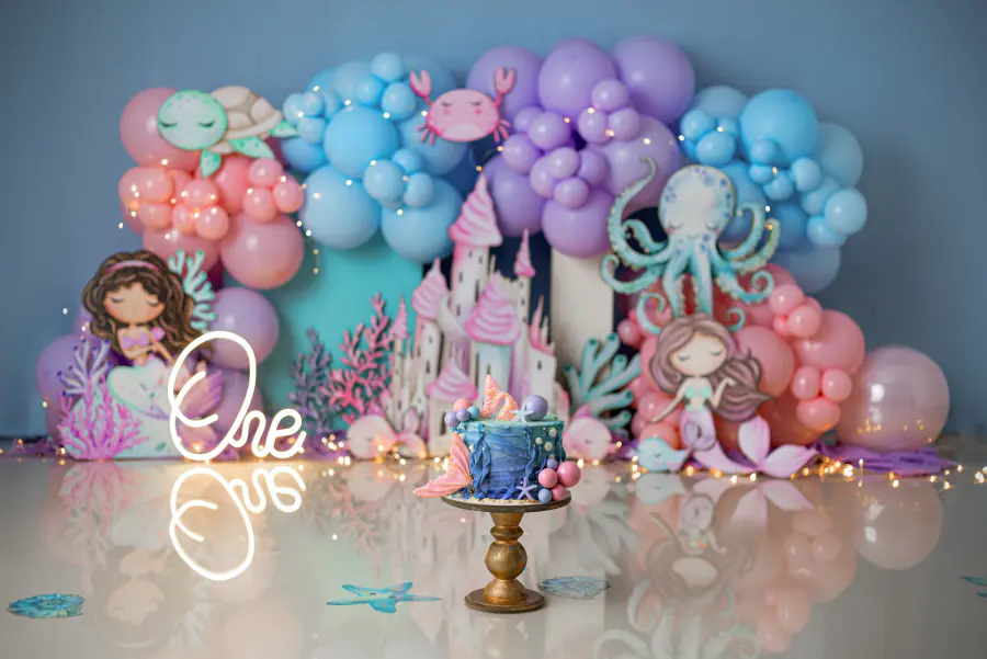 Escenario de sirenas con globos lila y turquesa, castillo y pastel
